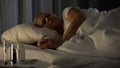 Middle-aged lady sleeping in bed, treatment pills table, health care, medicine