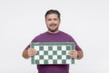 A middle aged male chess player holding a tournament sized chessboard. An avid hobbyist isolated on a white background Royalty Free Stock Photo