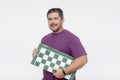 A middle aged male chess player holding a tournament sized chessboard. An avid hobbyist isolated on a white background