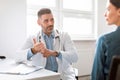 Middle aged male doctor having conversation with female patient, general practitioner consulting lady Royalty Free Stock Photo