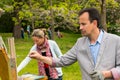 Middle-aged male and female artists painting in the open air