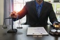 Middle-aged male lawyer working with legal contract documents in court room Justice with tee hammer and black scales on table, Royalty Free Stock Photo