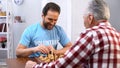 Middle aged male volunteer playing chess with elderly man in nursing home, hobby