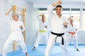 Middle-aged man attendee of karate classes practicing kata standing in row with others Royalty Free Stock Photo