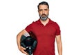 Middle aged man with beard holding motorcycle helmet thinking attitude and sober expression looking self confident Royalty Free Stock Photo