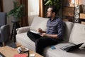 A middle-aged man with a beard is sitting on a couch with an English dictionary in his hands. The boy is trying to Royalty Free Stock Photo