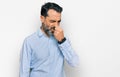Middle aged man with beard wearing business shirt smelling something stinky and disgusting, intolerable smell, holding breath with Royalty Free Stock Photo