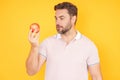 Middle aged man bitting apple, healthy lifestyle. Man holds a fresh green apple studio portrait on yellow isolated Royalty Free Stock Photo