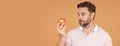 Middle aged man bitting apple, healthy lifestyle. Man holds a fresh apple studio portrait on beige isolated background