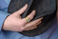 A middle-aged man in a blue shirt clutches his hat.