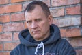 Middle-aged man, brooding, in a sweatshirt with a hood,