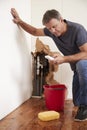 Middle aged man with a burst pipe dialling phone for help