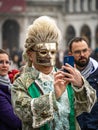 A middle-aged man in a carnival costume and a mask takes a selfie at the carnival in Venice, Italy