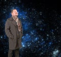 Middle-aged man in a coat looking up on starry universe background Royalty Free Stock Photo