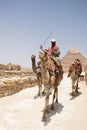 Man sitting on a camel riding away from the famous pyramids at gizeh egypt. Royalty Free Stock Photo