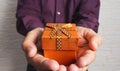 Man giving a holiday present wrapped in golden ribbon, hands holding gift box. Holiday, Christmas or Birthday concept Royalty Free Stock Photo