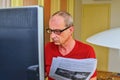 Middle aged man with glasses sitting at desk. Mature man using personal computer. Senior concept. Man and paperwork. Pensive man