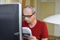 Middle aged man with glasses sitting at desk. Mature man using personal computer. Senior concept. Man and paperwor