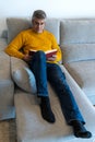 Middle-aged man with glasses sitting on the sofa reading a book Royalty Free Stock Photo