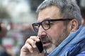 Middle-aged man with a gray beard and glasses talking on a mobile and looking sideways Royalty Free Stock Photo