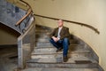 A middle-aged man in a green jacket sits on the steps of a semicircular staircase Royalty Free Stock Photo