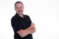 Middle aged man handsome with crossed arms folded in black t shirt looking at camera and posing in studio over white background Royalty Free Stock Photo