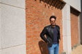 Middle-aged man, handsome and dark, bearded and with a sculpted body on a brick wall. Man wearing black leather jacket, mirrored Royalty Free Stock Photo