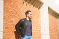 Middle-aged man, handsome and dark, bearded and with a sculpted body on a brick wall. Man wearing black leather jacket, mirrored Royalty Free Stock Photo