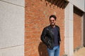 Middle-aged man, handsome and dark, bearded and with a sculpted body on a brick wall. Man wearing black leather jacket, mirrored Royalty Free Stock Photo