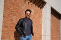 Middle-aged man, handsome and dark, bearded and with a sculpted body on a brick wall. Man wearing black leather jacket, mirrored Royalty Free Stock Photo