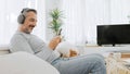 Middle-aged man in headphones using smartphone on sofa Royalty Free Stock Photo