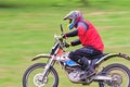 Middle aged man during hobby ride on his backyard on electric KTM motocross bike on a field.
