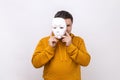 Middle aged man holding white mask, covering face, serious expression, multiple personality. Royalty Free Stock Photo