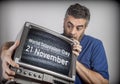 Middle-aged man holds a TV with World Television Day 21 November screen