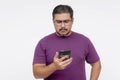 A middle aged man looking confounded and stumped while looking at his cellphone. Wearing eyeglasses and a purple waffle shirt, Royalty Free Stock Photo