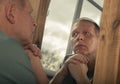 Middle-aged man looking at mirror reflection seriously, thinking about his age and life Royalty Free Stock Photo