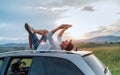 Middle-aged Man lying on the car roof and reading the paper bestseller book.He stopped his auto on the meadow with a beautiful Royalty Free Stock Photo