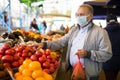 Middle aged man in mask buying tomatoes Royalty Free Stock Photo