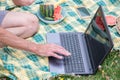 middle aged man with mobile phone and laptop lies on a blanket in green grass Royalty Free Stock Photo