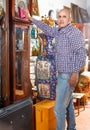 Middle aged man owner of antiques shop wiping vintage goods Royalty Free Stock Photo