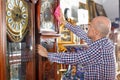 Middle aged man owner of antiques shop wiping vintage goods