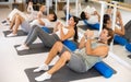 Middle-aged man practicing pilates with roller on gray mat in gym room