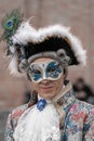 A middle-aged man in a red vintage costume with a lace collar, wearing a carnival mask, tricorn hat with feathers, with big brooch Royalty Free Stock Photo