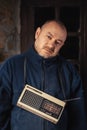 A middle-aged man with a retro radio looks at the camera. Dark background Royalty Free Stock Photo