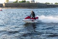 A middle-aged man rides a jet ski on the Neva River in the center of St. Petersburg. Warships on the background. Sunny day. Summer