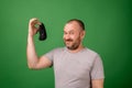 A middle-aged man shows a dirty sock on a green background. Laundry, hygiene, smelly feet concept Royalty Free Stock Photo