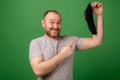 A middle-aged man shows a dirty sock on a green background. Laundry, hygiene, smelly feet concept Royalty Free Stock Photo