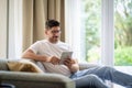 Middle-aged man sitting at home on the sofa and holding digital tablet in his hand Royalty Free Stock Photo