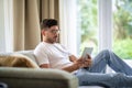 Middle-aged man sitting at home on the sofa and holding digital tablet in his hand Royalty Free Stock Photo