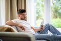 Middle-aged man sitting at home on the sofa and holding digital tablet in his hand Royalty Free Stock Photo